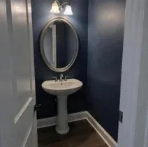 Powder room painted navy with crisp white trim in a Kelowna home