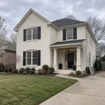 Brick house exterior painted a uniform warm white with breathable masonry paint