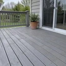 Weathered deck boards restained grey beside a patio door
