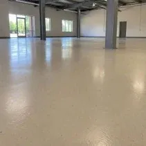 Beige epoxy floor coating in an empty commercial shop space