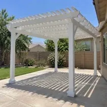 Backyard pergola freshly painted white over a patio in Kelowna