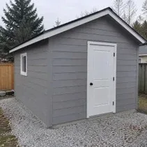 Small outbuilding painted grey with a new door