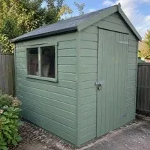 Wooden shed repainted sage green around the window